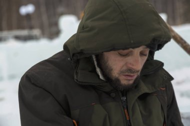 Bir işçi bir buz şehir düzenlenmesine meşgul bir kukuleta ile yeşil ceketli portresi