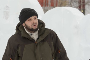 Bir işçi bir buz şehir düzenlenmesine meşgul bir kukuleta ile yeşil ceketli portresi