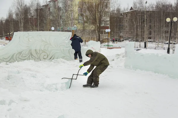 The worker pulls the ice block around the ice camp assembly site with forceps
