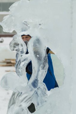 Heykeltıraş, buzdan bir heykeli Noel için keskiyle kesiyor.