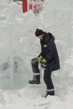 İşçi buz şehrin montaj yerinde elinde testere ile