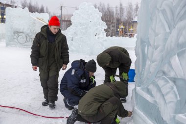 Elektrikçiler Buz figürleri aydınlatmak için bir güç kablosunu bağlama.