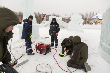 Elektrikçiler Buz figürleri aydınlatmak için bir güç kablosunu bağlama.