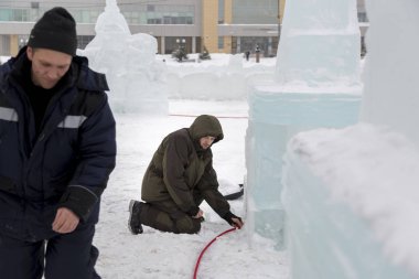 Elektrikçiler Buz figürleri aydınlatmak için bir güç kablosunu bağlama.