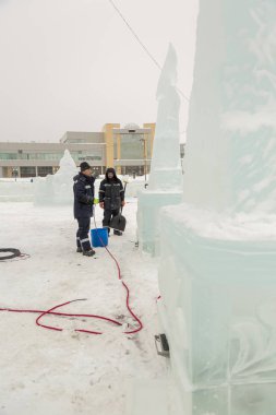 Elektrikçiler Buz figürleri aydınlatmak için bir güç kablosunu bağlama.