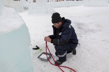 Elektrikçi Buz figürleri aydınlatmak için güç kablosunun ucunu temizler