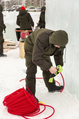 Elektrikçi Buz figürleri aydınlatmak için güç kablosunu bağlar.