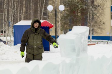 Bir işçi bir buz şehir düzenlenmesine meşgul bir kukuleta ile yeşil ceketli portresi