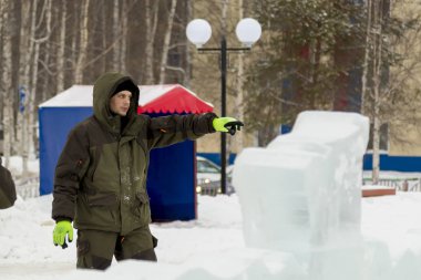 Bir işçi bir buz şehir düzenlenmesine meşgul bir kukuleta ile yeşil ceketli portresi