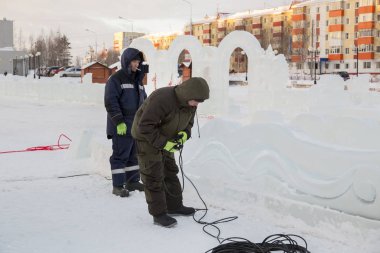 Elektrikçiler Buz figürleri aydınlatmak için bir güç kablosunu bağlama.