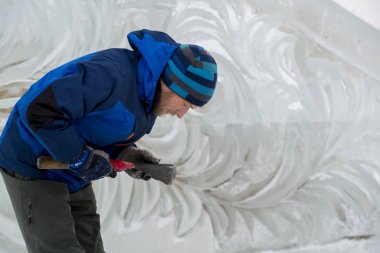 Heykeltıraş Noel için buz kalıbından bir buz heykeli kesiyor.