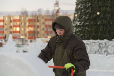 Bir işçi bir buz şehir düzenlenmesine meşgul bir kukuleta ile yeşil ceketli portresi