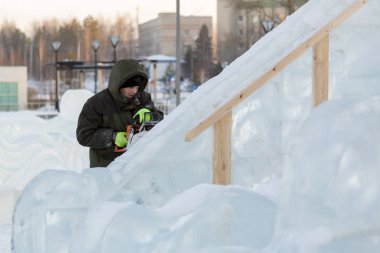Bir işçi bir buz şehir düzenlenmesine meşgul bir kukuleta ile yeşil ceketli portresi