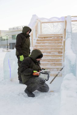 Elinde elektrikli testereyle çalışan bir işçi, buz bloğunun altını oyuyor.