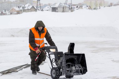Alt başlık ve bir kar temizleme aracı ile yansıtıcı yelek ile yeşil ceketli