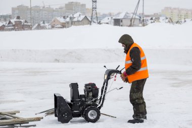 Alt başlık ve bir kar temizleme aracı ile yansıtıcı yelek ile yeşil ceketli