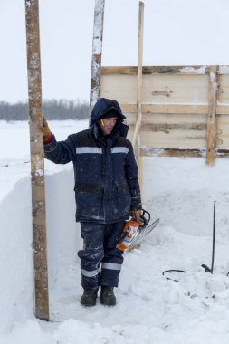 Montaj alanında elinde testere olan bir işçi.