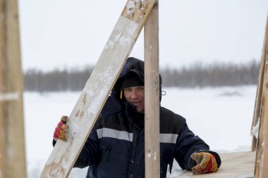Mavi bir ceket ve kukuleta ve kafasında siyah örme şapka işçi