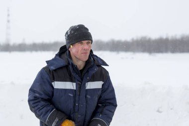 Mavi bir ceket ve kukuleta ve kafasında siyah örme şapka işçi