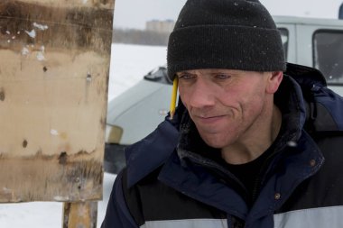 Mavi bir ceket ve kukuleta ve kafasında siyah örme şapka işçi