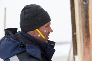 Mavi bir ceket ve kukuleta ve kafasında siyah örme şapka işçi