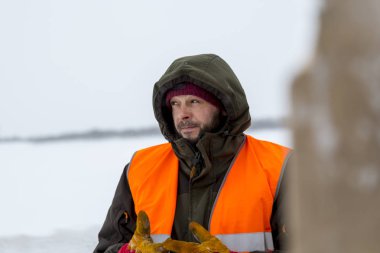 Yeşil bir ceket kukuIeta ve yansıtıcı yelek işyerinde işçi