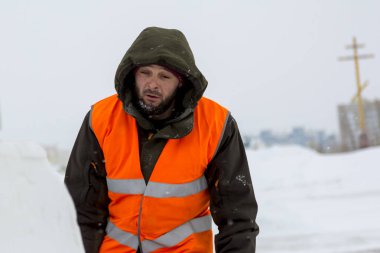 Yeşil bir ceket kukuIeta ve yansıtıcı yelek işyerinde işçi