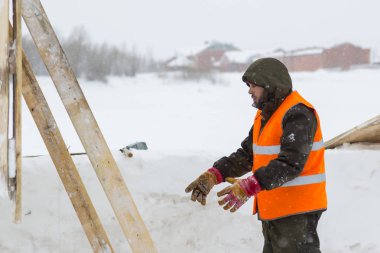 Yeşil bir ceket kukuIeta ve yansıtıcı yelek işyerinde işçi