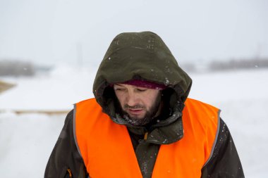 Yeşil bir ceket kukuIeta ve yansıtıcı yelek işyerinde işçi