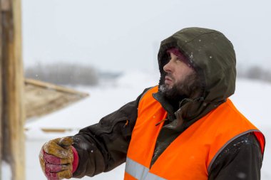 Yeşil bir ceket kukuIeta ve yansıtıcı yelek işyerinde işçi