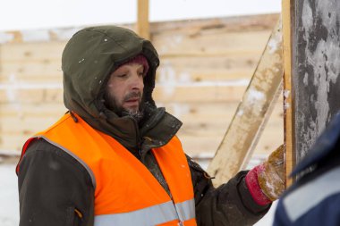 Yeşil bir ceket kukuIeta ve yansıtıcı yelek işyerinde işçi