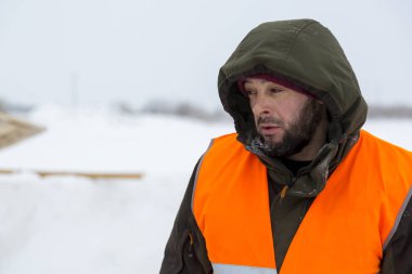 Yeşil bir ceket kukuIeta ve yansıtıcı yelek işyerinde işçi