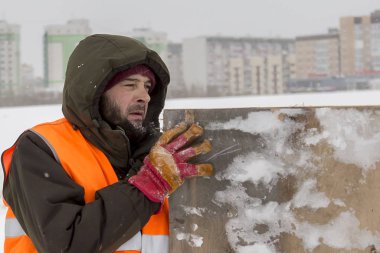 Yeşil bir ceket kukuIeta ve yansıtıcı yelek işyerinde işçi