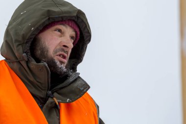 Yeşil bir ceket kukuIeta ve yansıtıcı yelek işyerinde işçi