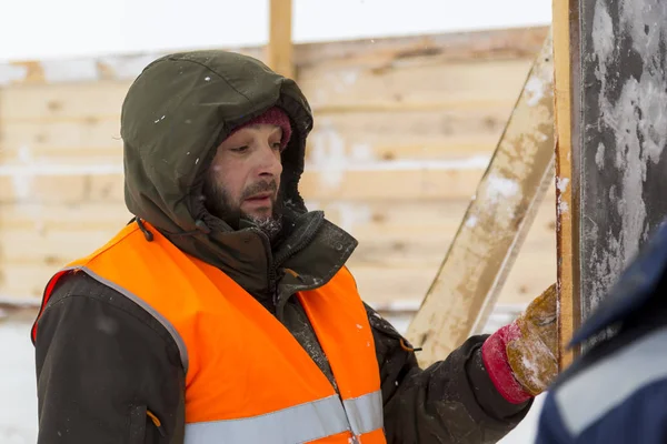 Yeşil bir ceket kukuIeta ve yansıtıcı yelek işyerinde işçi