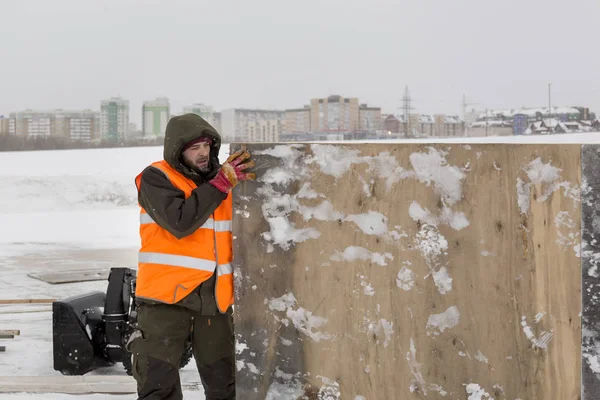 Yeşil bir ceket kukuIeta ve yansıtıcı yelek işyerinde işçi