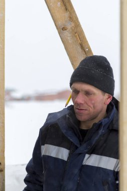 Mavi bir ceket ve kukuleta ve kafasında siyah örme şapka işçi