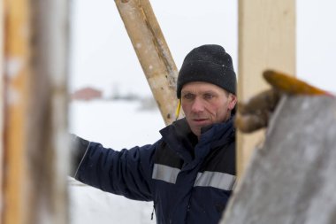 Mavi bir ceket ve kukuleta ve kafasında siyah örme şapka işçi