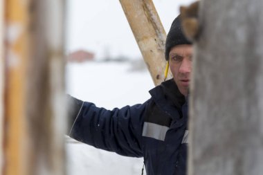 Mavi bir ceket ve kukuleta ve kafasında siyah örme şapka işçi