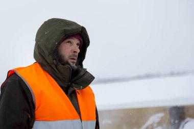 Yeşil bir ceket kukuIeta ve yansıtıcı yelek işyerinde işçi