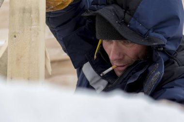 Mavi bir ceket ve kafasında bir kukuleta ile bir işçi ve bir sigara ağzında portre