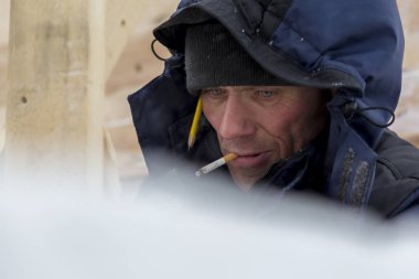 Mavi bir ceket ve kafasında bir kukuleta ile bir işçi ve bir sigara ağzında portre