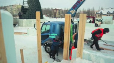 Turuncu yelekli bir işçi arabasından buz parçaları indirmekle meşgul..