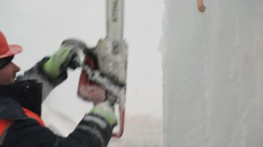 Turuncu yansıtıcı yelek ve kask takan işçiler elektrikli testere buz tabakasını özelleştirdiler