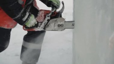 Turuncu yansıtıcı yelek ve kask takan işçiler elektrikli testere buz tabakasını özelleştirdiler