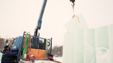 İşçiler bir arabadan buz kalıpları indiriyorlar. Toplayıcılar vinç kullanarak bir arabadan buz panelleri indiriyorlar.