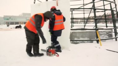 Montajcılar yüksek buz bloklarına ladin koyarlar buz kasabasının inşaatçıları Noel ağacını yüksek buz panelleriyle kaplarlar.