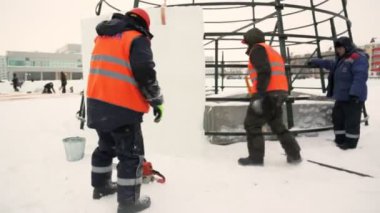 Montajcılar yüksek buz bloklarına ladin koyarlar buz kasabasının inşaatçıları Noel ağacını yüksek buz panelleriyle kaplarlar.