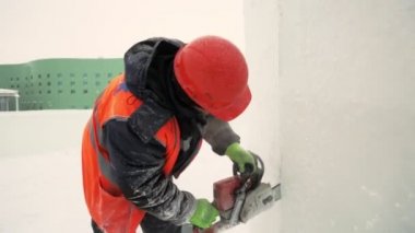 Turuncu yansıtıcı yelek ve kask takan işçiler elektrikli testere buz tabakasını özelleştirdiler