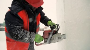 Turuncu yansıtıcı yelek ve kask takan işçiler elektrikli testere buz tabakasını özelleştirdiler